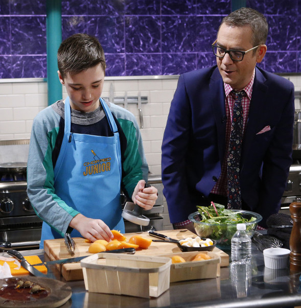 Host Ted Allen checks in on junior chef Moses Hausmann as he cooks with lomo Iberico, baby rainbow chard, gummy eggs over easy and apricots during the entree round as seen on Food Network's Chopped Junior, Season 2.